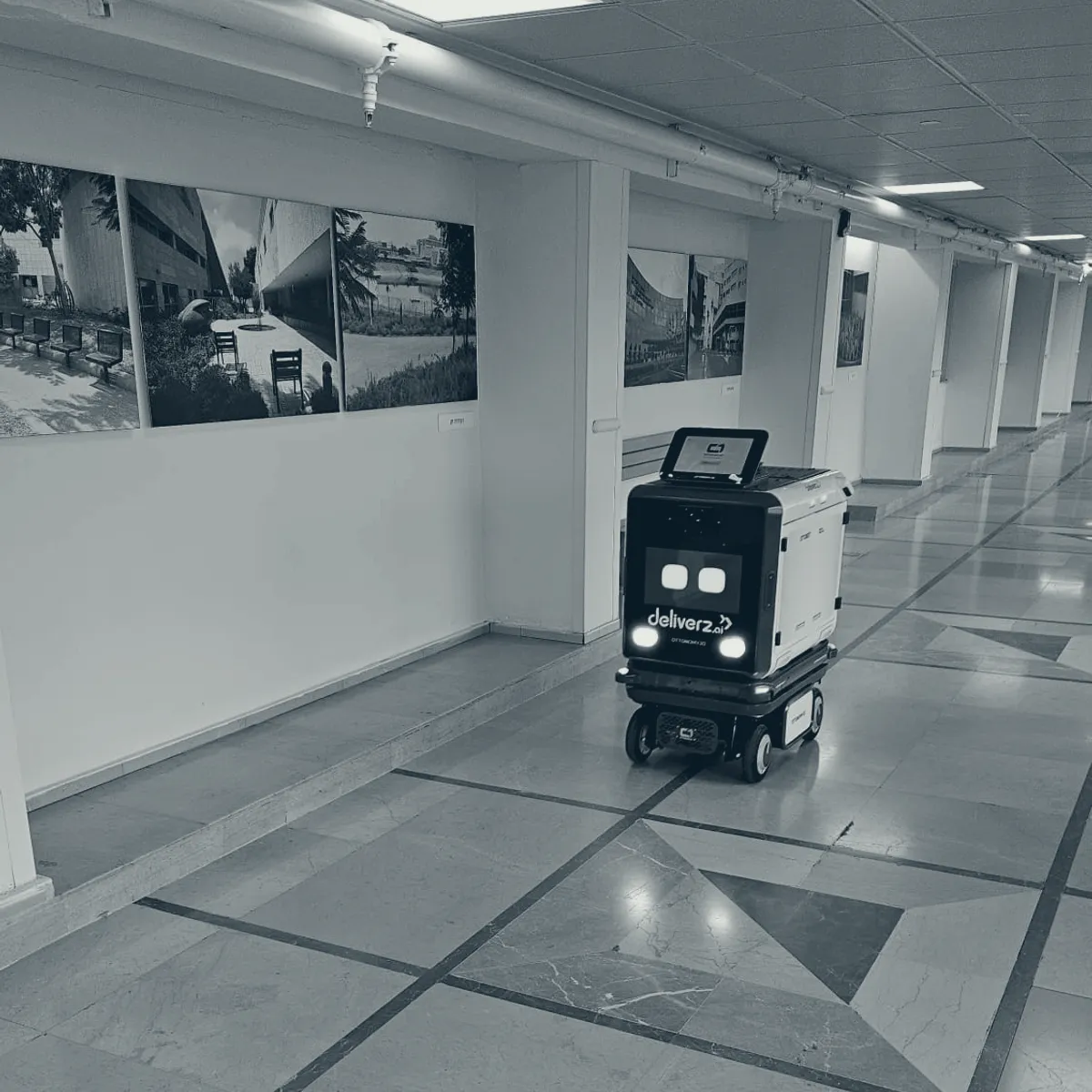 A delivery robot crossing a hospital corridor on its own, between buildings.